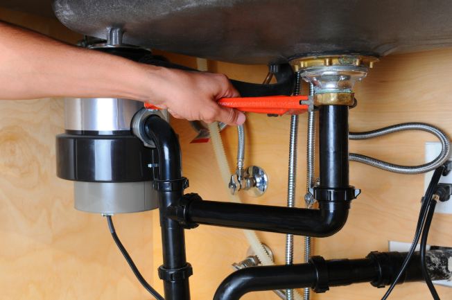 YES! technician's hand, holding wrench, repairing garbage disposal pipe in Salt Lake City, UT, home.