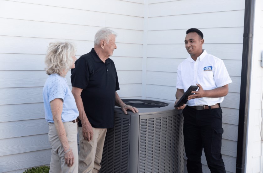 YES! HVAC technician in Provo, UT, speaking to couple about services outside their home.