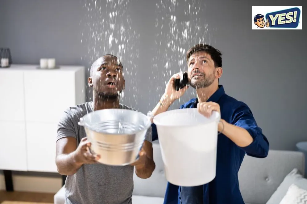 Two worried men in a home holding buckets, catching water pouring from above leaking water pipe.