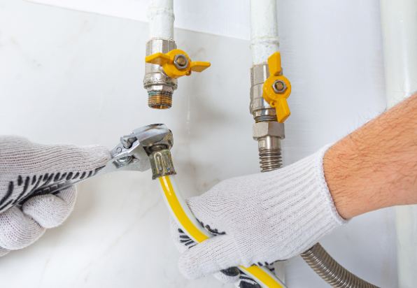 YES! technician's gloved hands, holding a wrench and a gas line to connect to complete a gas line installation service in a Salt Lake City, UT, home.